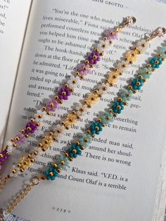 an open book with three different colored beads on it and a chain that is attached to the page