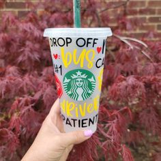 a hand holding up a starbucks cup with the word drop off on it and red leaves in the background