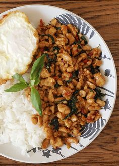 a white plate topped with rice and meat next to an egg on top of it