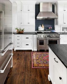 a kitchen with white cabinets, black counter tops and stainless steel appliances in the center