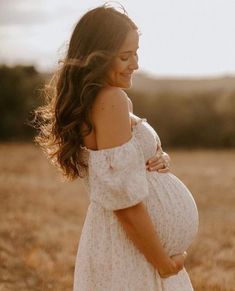 a pregnant woman is standing in a field