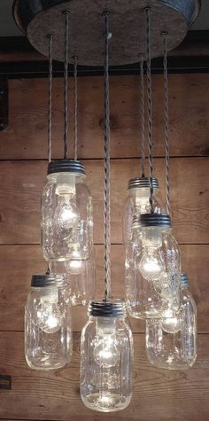 mason jar chandelier with lights hanging from it's sides on a wooden wall