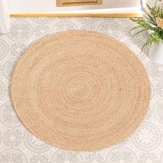 a round rug on the floor in front of a door with flowers next to it