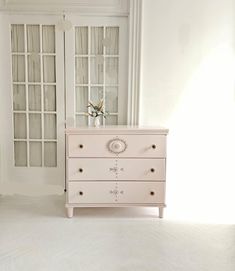 a white dresser sitting in front of two glass doors