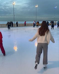 two people skating on an ice rink at dusk