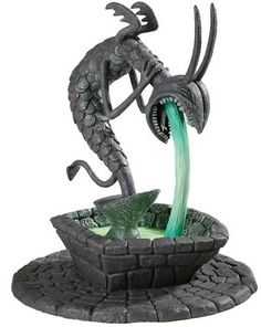 a statue of a dragon drinking out of a fountain with water pouring from it's mouth