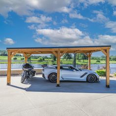 a white sports car parked in front of a wooden carport with a motorcycle underneath