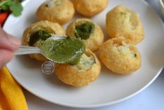 a white plate topped with mini food and a green dipping sauce on top of it