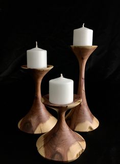 three wooden candlesticks with white candles in them