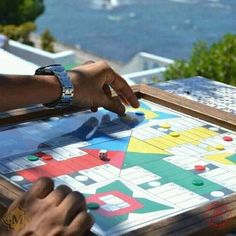 two people playing a board game on top of a table with water in the background