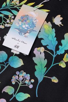 a card is laying on top of a black fabric with blue and green flowers in it