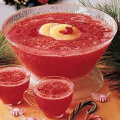 two glasses filled with red liquid and candy canes