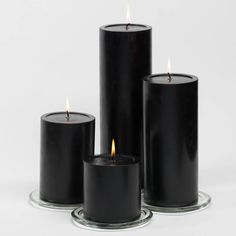 three black candles sitting next to each other on top of a glass plate with one burning