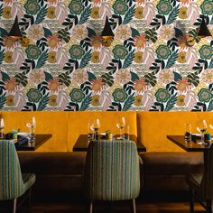 the interior of a restaurant with yellow booths and patterned wall paper on the back wall