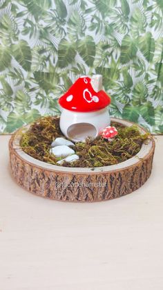 a small red and white mushroom house sitting on top of a tree stump with moss