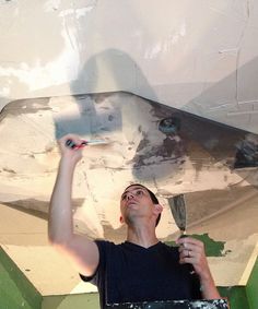 a man is painting the ceiling with white paint on it and holding a brush in his hand