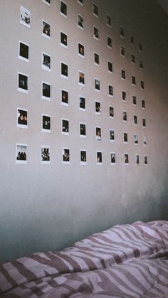 a bed with pink sheets and pictures on the wall next to it's headboard