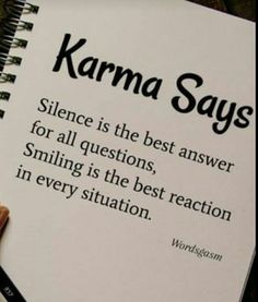 a person holding a book with the words karma says written on it, in front of them