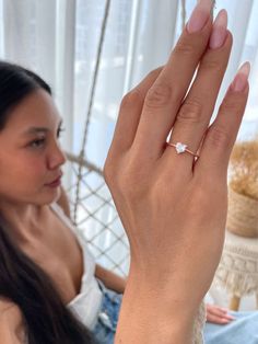 a woman sitting on a couch holding up her hand with a diamond ring in it