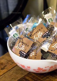 a white bowl filled with lots of brown and black candies on top of a wooden table