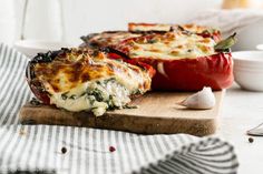 two stuffed peppers sitting on top of a wooden cutting board