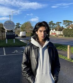 a young man standing in the middle of a road with his hands on his hips