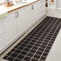 a kitchen with white cabinets and black rug