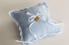 a blue pillow with a gold ring on the front and white ribbon tied around it