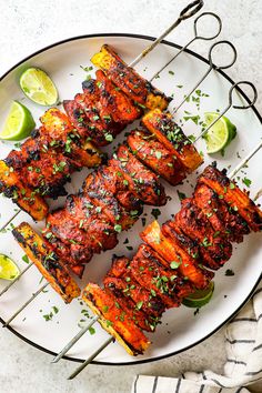 chicken skewers on a white plate with limes and cilantro