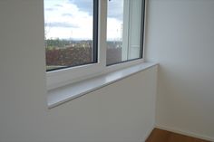 an empty room with two windows and a wooden floor in front of the window is a white wall