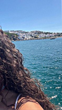 the back of a woman's head as she looks out over the water from a boat