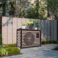 an outdoor planter with flowers and plants on it in front of a fenced area