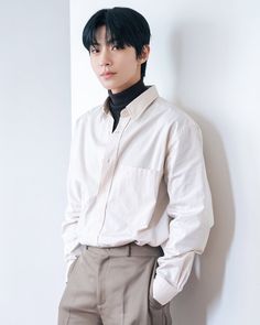 a young man is leaning against a wall wearing a white shirt and khaki pants