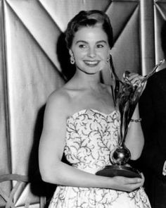 a man and woman standing next to each other holding an award