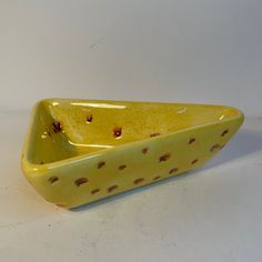 a yellow ceramic bowl with brown spots on it