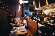 a group of people sitting at a table in a restaurant with food on the counter