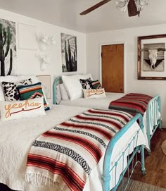 two beds in a room with pictures on the wall