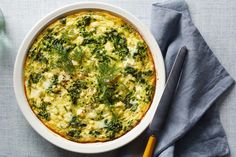 a casserole dish with spinach and cheese in it on a blue cloth