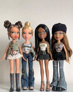 three dolls are standing next to each other in front of a white wall and one has her hair pulled back