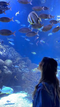 a woman looking at fish in an aquarium