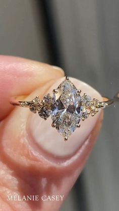 a close up of a person's hand holding an engagement ring