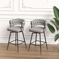 two gray chairs sitting on top of a wooden floor next to a plant in a vase