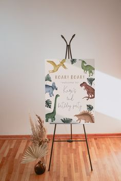 an easel with dinosaurs on it in front of a white wall and wooden floor