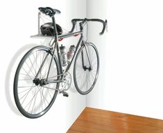 a bike mounted to the side of a wall next to a wooden floor and white walls