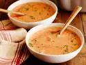 two bowls of soup on a wooden table