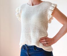 a woman is wearing a crochet top with ruffles on the sleeves