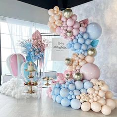 a balloon arch is decorated with pastel colors and gold accents for a birthday party