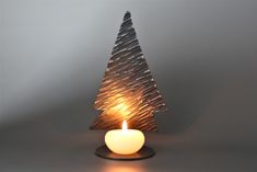 a lit candle sitting in front of a small christmas tree shaped like a pine cone