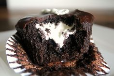 a piece of chocolate cake sitting on top of a paper plate with white frosting