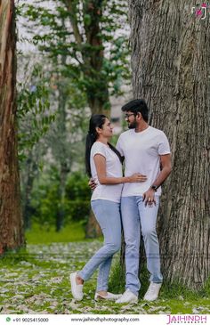 a man and woman standing in front of a tree